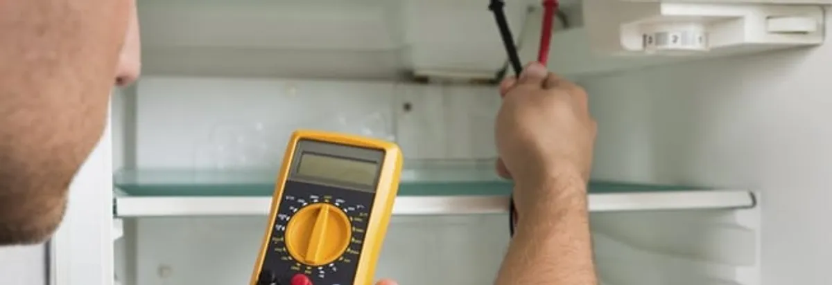 Refrigerator repair technician testing electrical components with a multimeter in Fort Wayne, IN