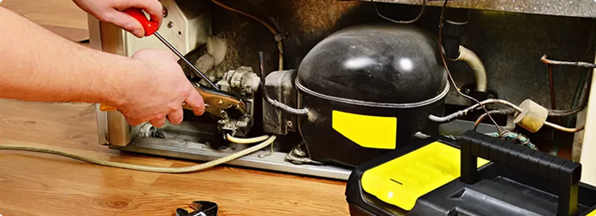 Refrigerator repair technician fixing the compressor and wiring in Fort Wayne, IN